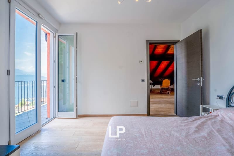 modern design, large windows, wooden floor, bed, white walls, balcony with railings, view of lake and mountains