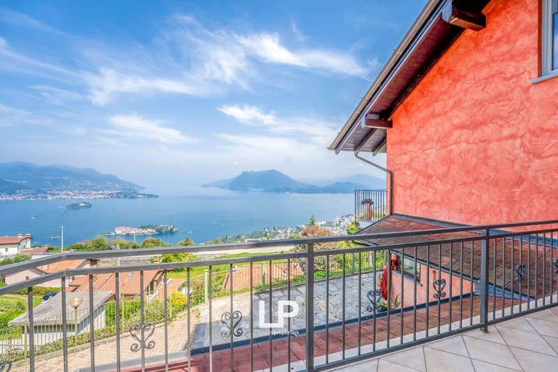 Balcony with railings, view of a lake, mountains, houses, red and orange building