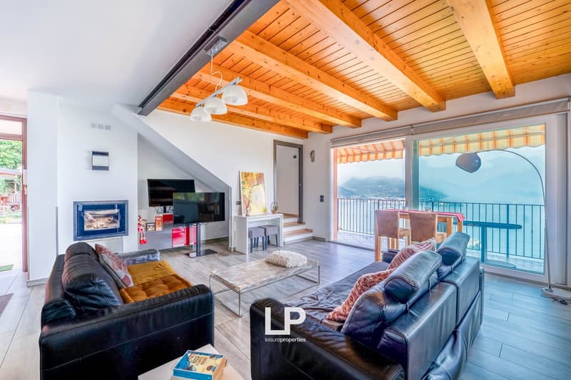 Open plan layout, black leather sofas, coffee table, TV, fireplace, sliding doors to balcony, glass coffee table, wooden ceiling