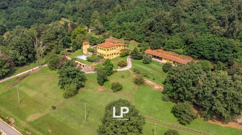 Large villa, multiple buildings, large pool, green landscape, red roofs
