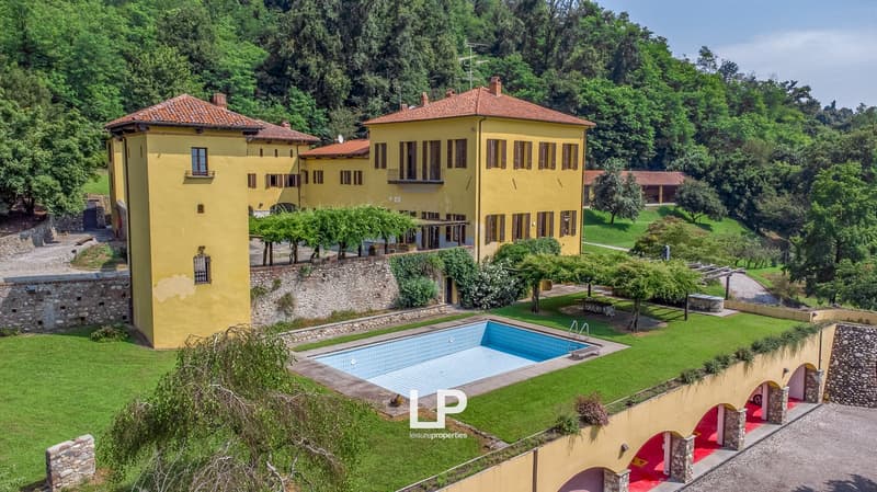 2 story villa, yellow exterior, red roof, swimming pool, hilly terrain, lush trees