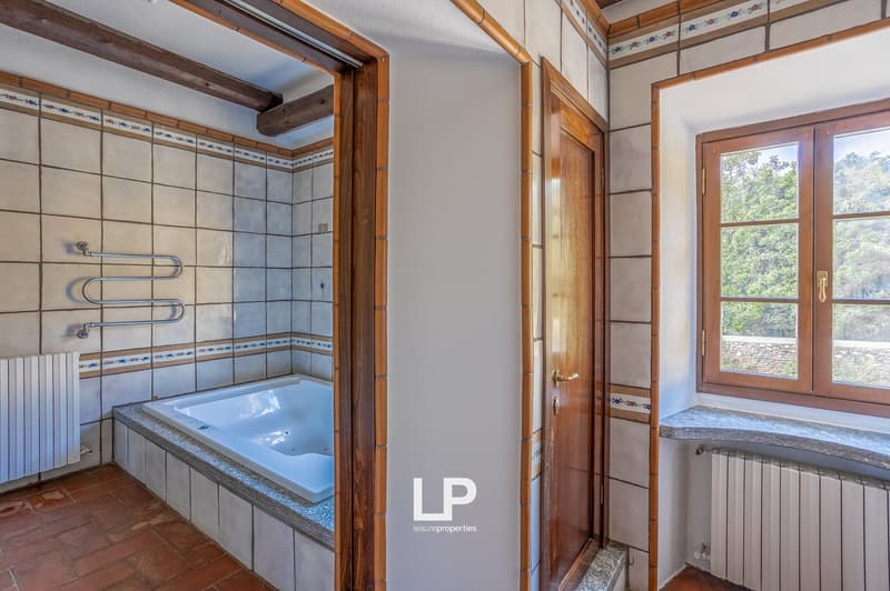 Bathtub, tiled walls, radiator, wooden floor, window with view