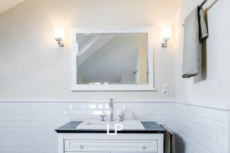 Bathroom: white walls, white tiled walls, mirror, white cabinet, sink, faucet, towel rack