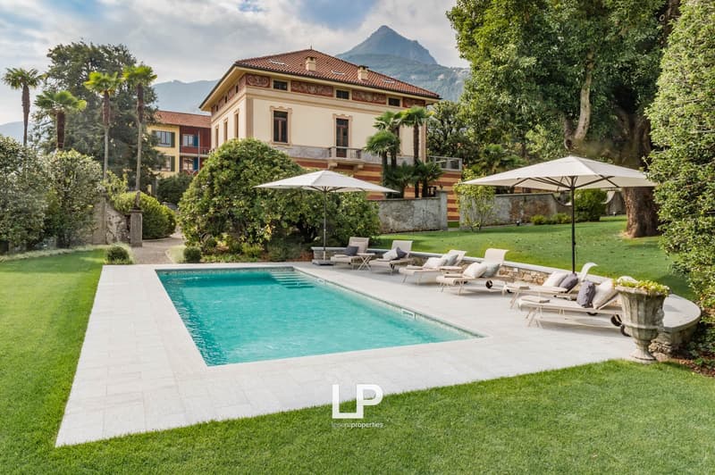 A large pool, surrounded by chairs and umbrellas, with a view of the mountains