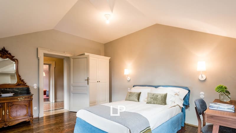 bedroom with bed, desk, armchair, lamp, closet, wooden floor, mirror