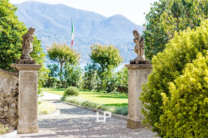 Gravel walkway, hedges, two statues, lake and mountains in the background