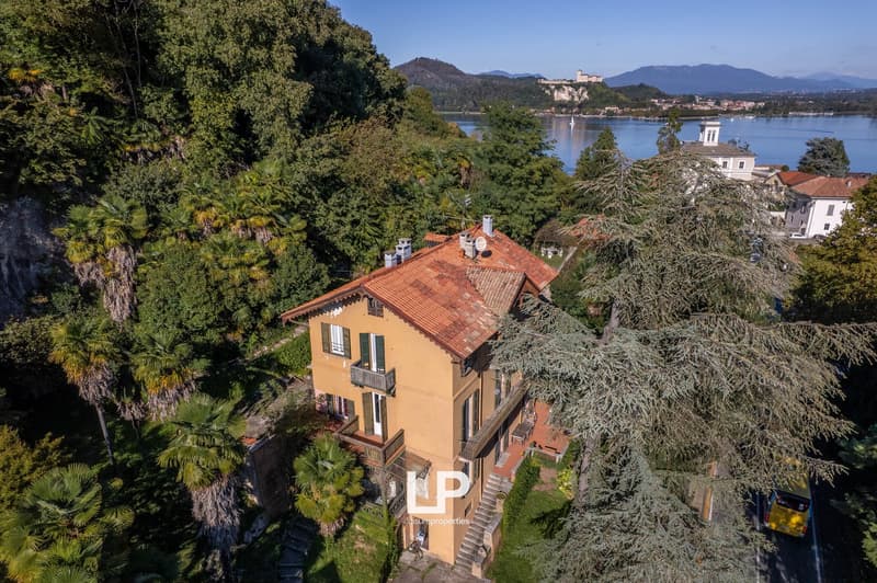 House: multi-level, yellow stucco, red roof, balcony, located on a hill