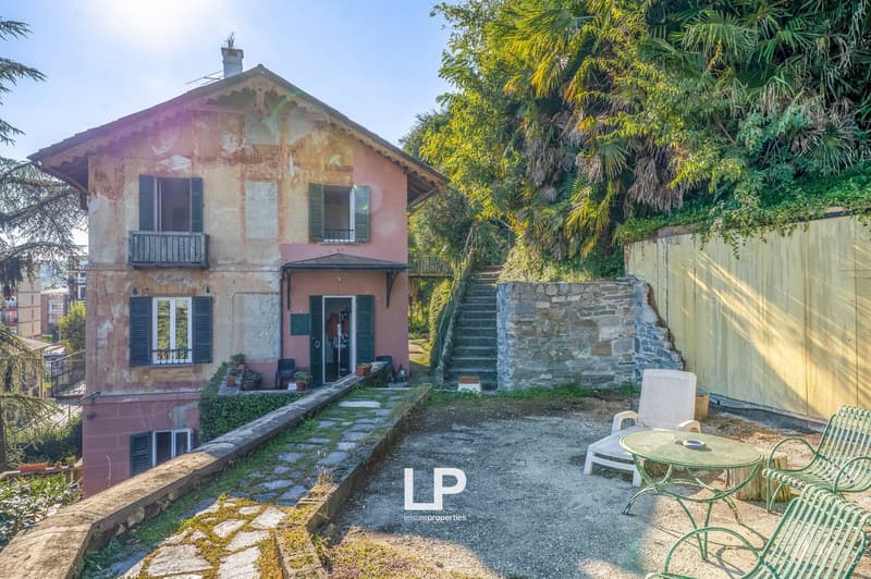 2 story house, wooden balconies, brick walls, patio with seating, garden