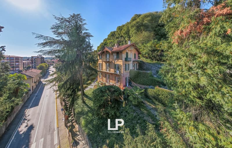 Three story villa, red roof, situated on a hill with greenery around