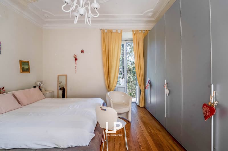 A bedroom with a bed, two armchairs, and a large window.