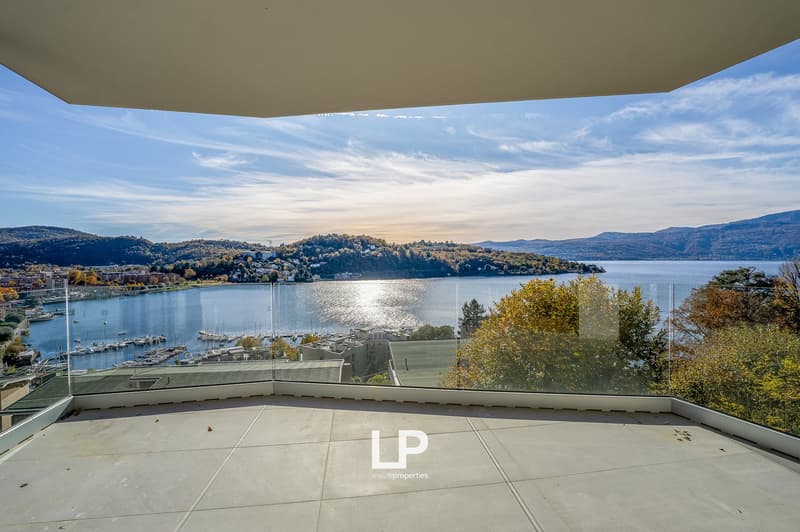 Terrace with glass railings, overlooking the lake, mountains, and town