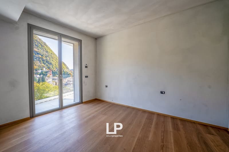 sliding glass doors leading to a balcony, wooden floor, white walls, scenic mountain view