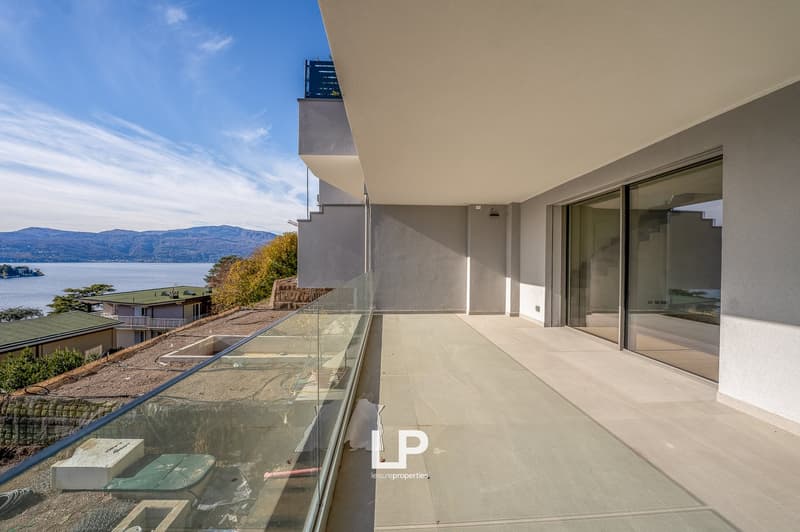 Outdoor terrace with glass railings, tiled floor, and lake view