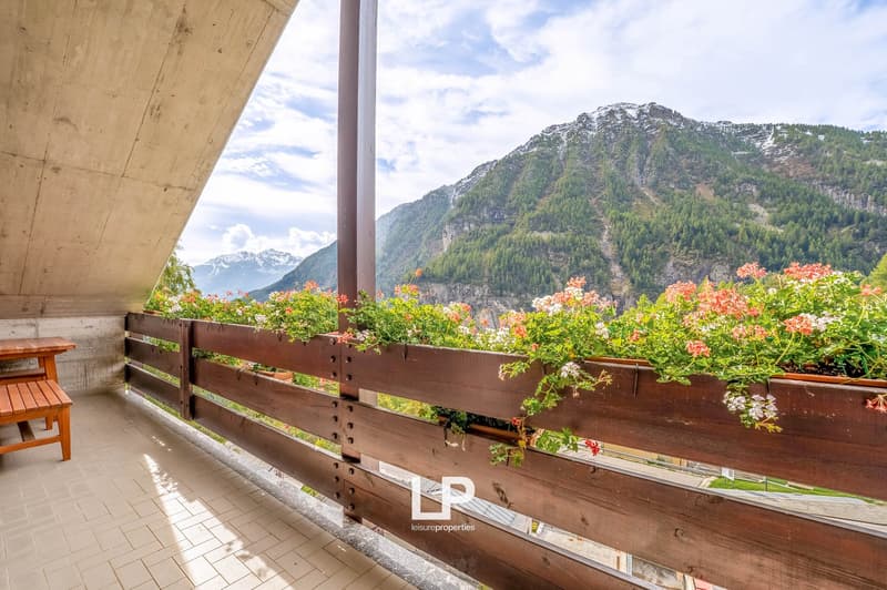 balcony with wooden railings, outdoor wooden table, wooden bench, planted flower pots, mountain view
