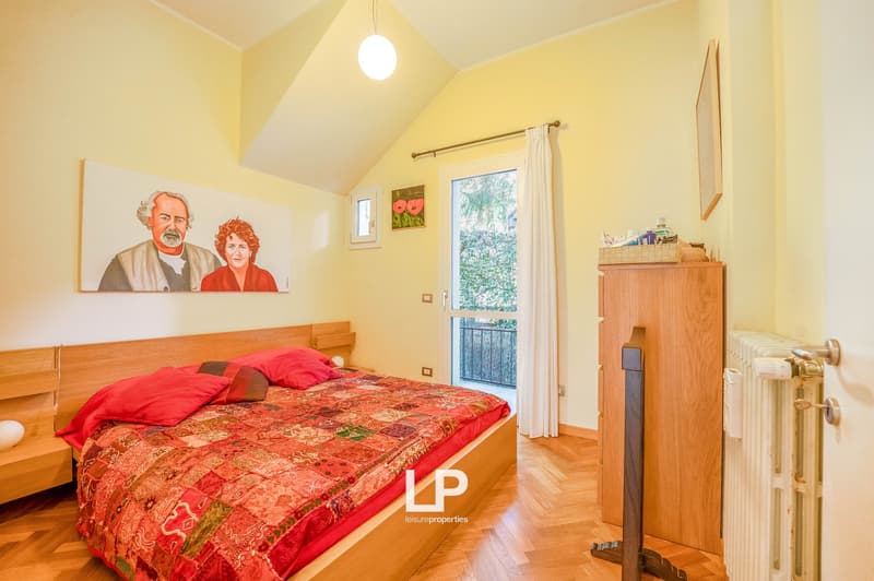 double bed with red cover, nightstands, white radiator, balcony