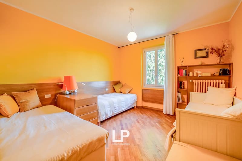 bedroom with wooden floor, three beds, window, curtains, a lamp, and a wooden cabinet with drawers
