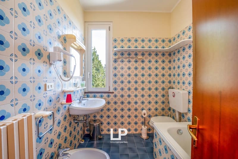 patterned tiles, white sink, white toilet, white bathtub, blue and white radiator