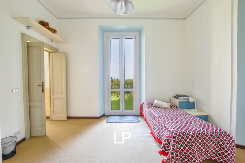 Single bed, night stand with lamp, entrance, balcony, double doors with window, carpet, light on ceiling