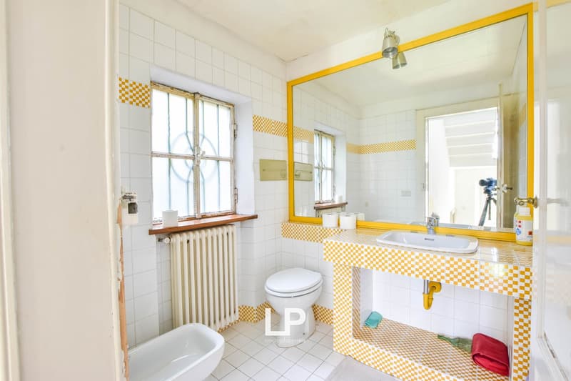 Bathroom with toilet, sink, mirror, radiator, window, tub, and checkered tile flooring.