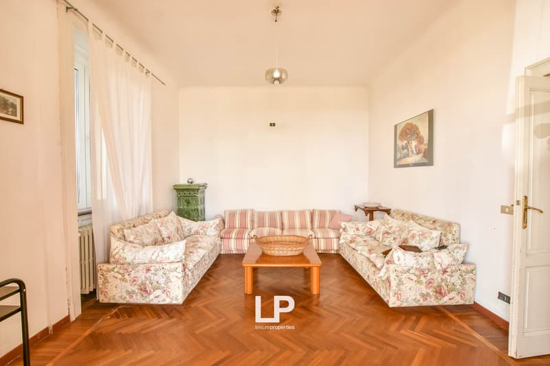 wooden floor, three sofas, central table, picture frames, radiator