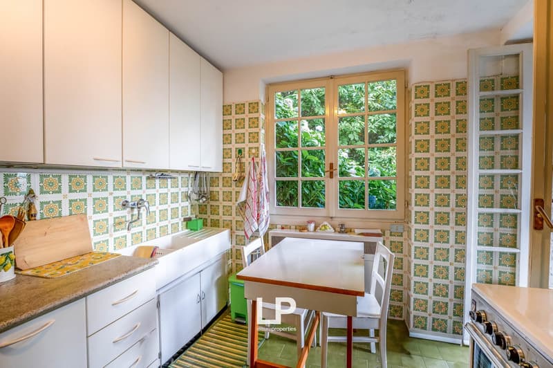 white cabinets, double sink, green tiles, window with view of trees