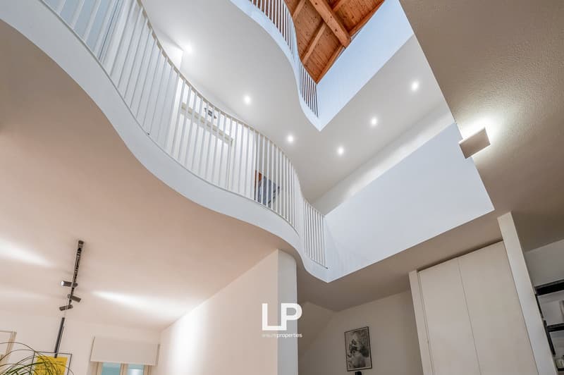 Modern interior design with open floor plan, wooden ceiling, white walls, balcony, and skylights