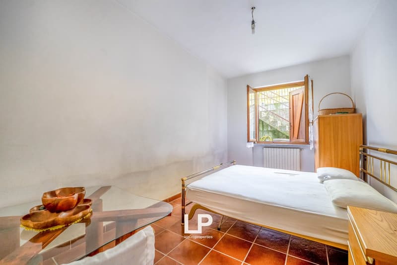 room with a double bed, glass table, white walls, and tile floor