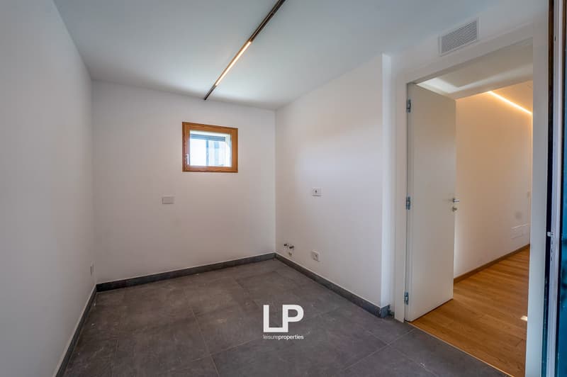 Empty room with tile flooring, white walls, power outlet, and small window