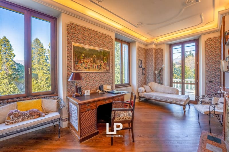 desk, lamp, sofa, 2 armchairs, couch with blanket, painting, windows, balcony, wooden floor, floral wallpaper