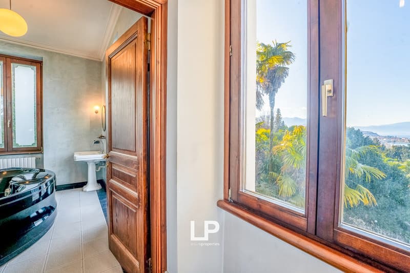 Bathroom with bathtub, sink, radiator, and large window with a view of trees and mountains