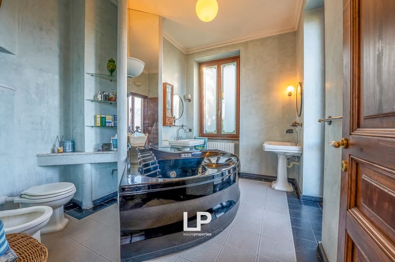 modern bathroom with large window, bidet, toilet, shower, bathtub, shelves, sink, mirror, radiator