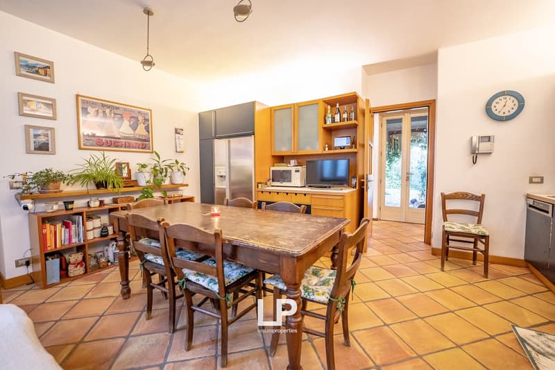 Wooden dining table, bookshelf, fridge, microwave, cabinets, television, tiled floor