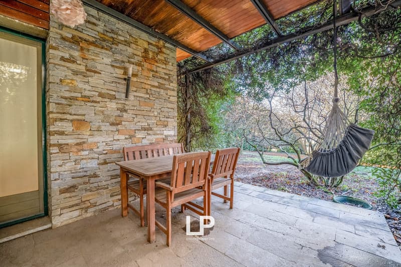 Outdoor wooden table and chairs, hammock, stone wall, roof, hanging candle, open window