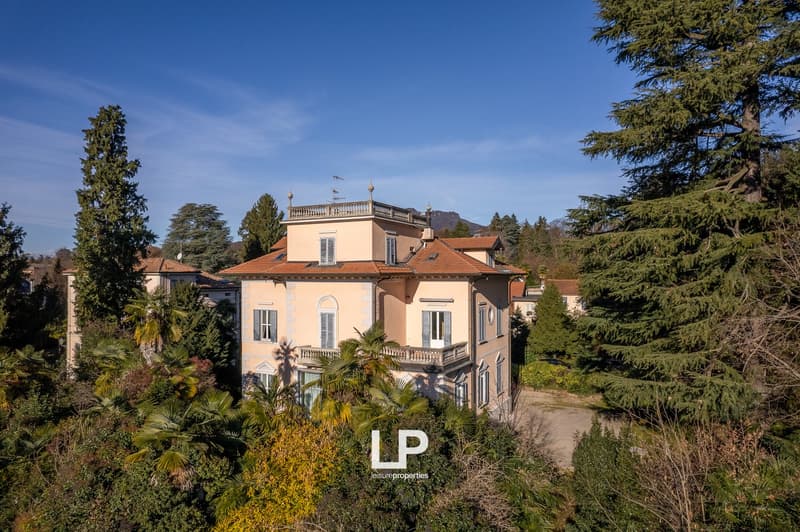 3 story house, beige facade, red roof, multiple windows, balcony, surrounded by trees