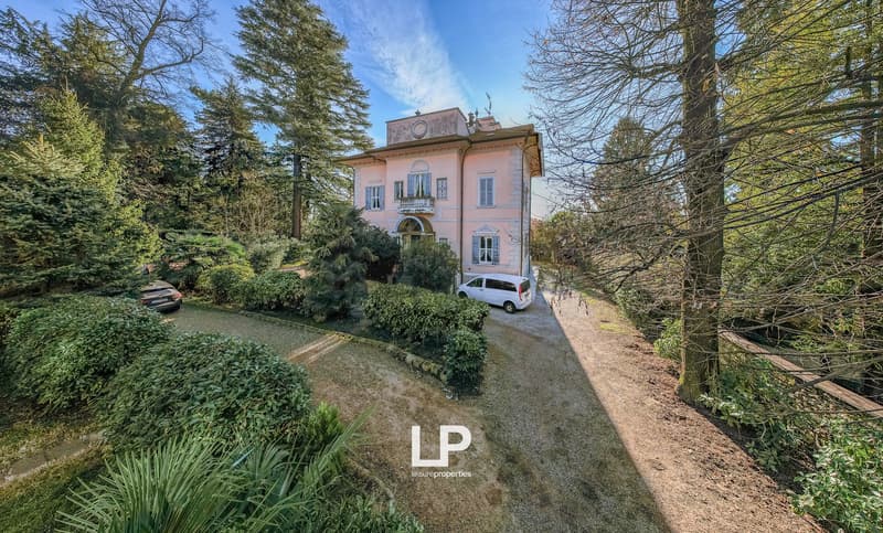 Two-story villa with trees around, car parked in front