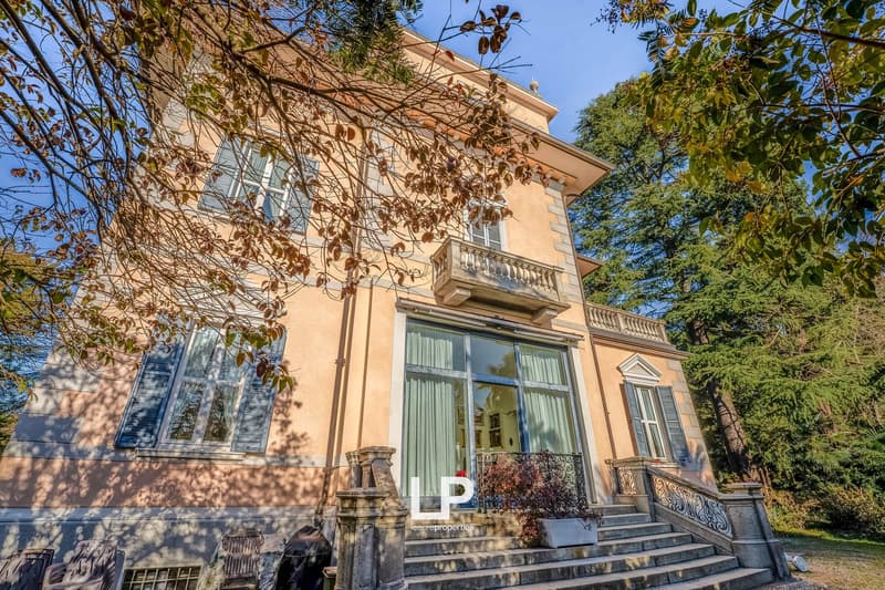 large building, beige brick facade, large windows, entrance with stairs and railing, terrace on the second floor
