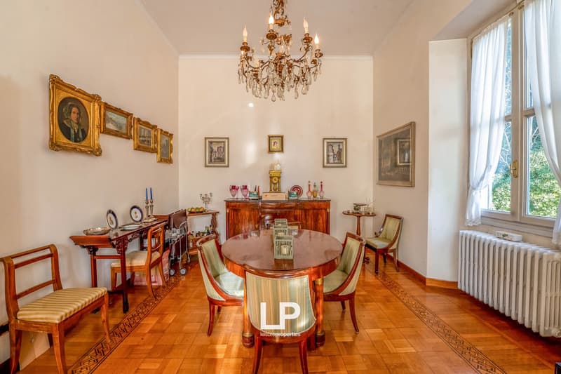 Large wooden table, antique chairs, buffet, large chandelier, artwork on wall, radiator