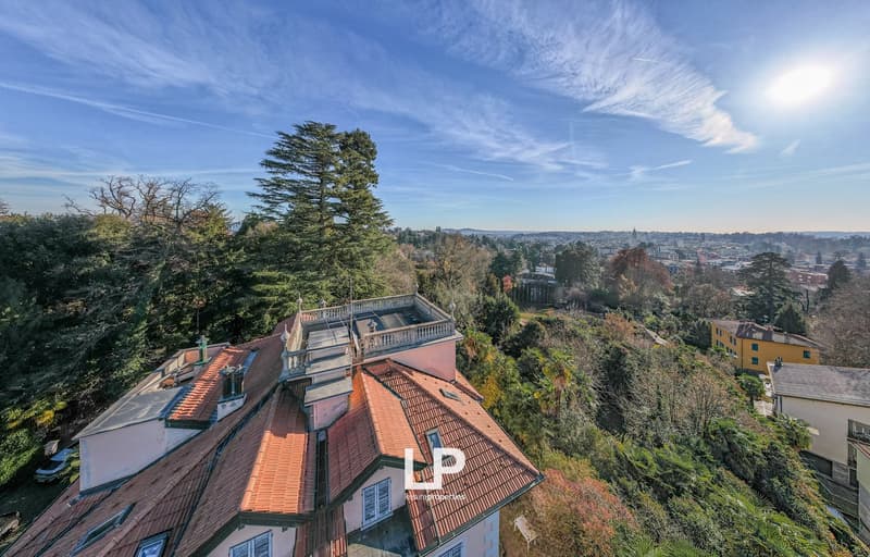 large building, elevated position, terracotta tiled roof, surrounded by trees, distant view of the city