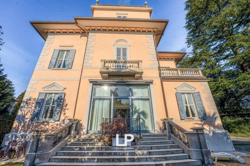 Large three story house with a balcon, glass window, plants, front stairs