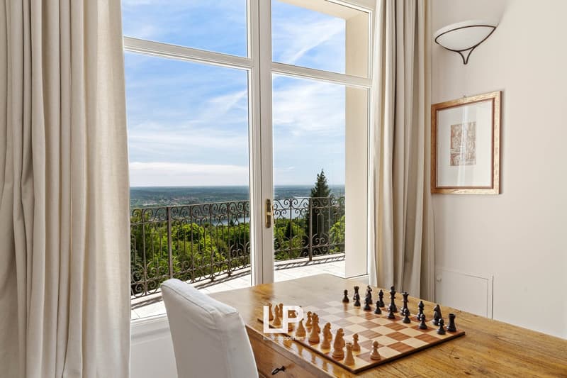 large windows with balcony, chess set on wooden table, framed picture on wall, modern design