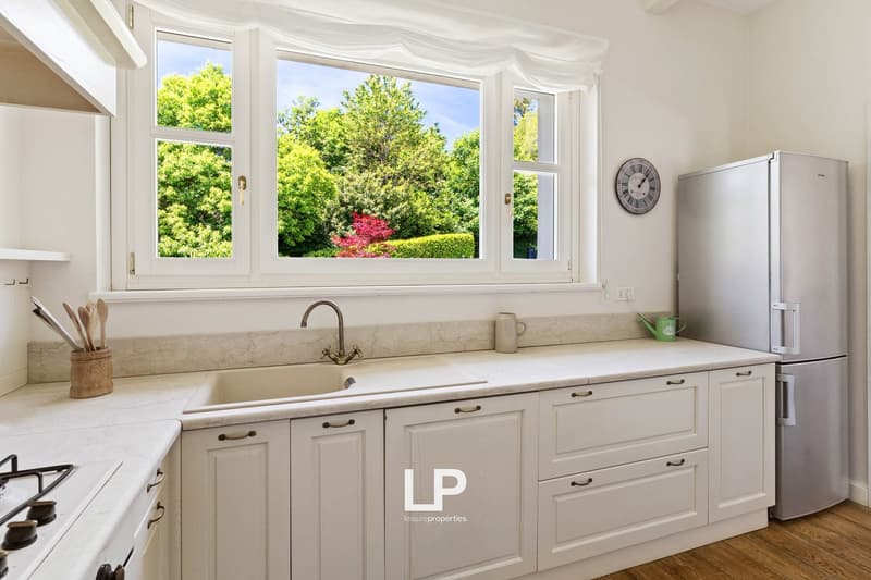 Modern kitchen with a sink, faucet, refrigerator, gas stove, and window with garden view