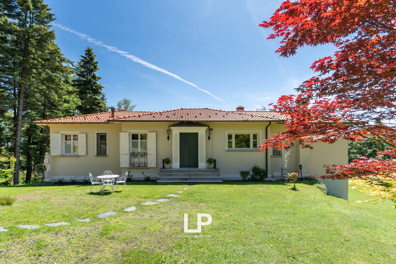 Two-story house, red roof, yellow walls, white shutters, well-manicured lawn, outdoor dining area