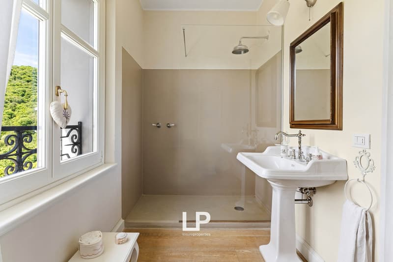 white walls, wooden floor, sink, mirror, shower with glass door