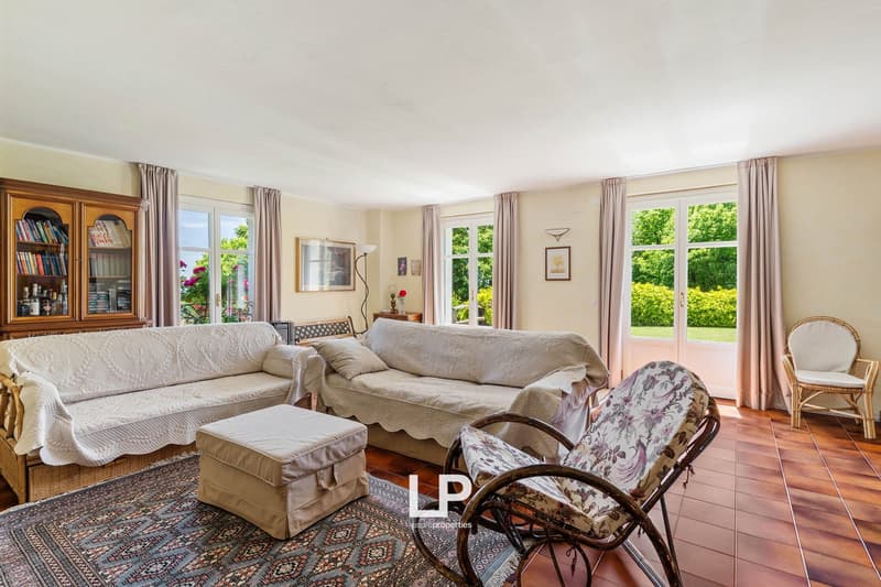modern decor, two couches, ottoman, wooden floor, rug, windows, picture frames, bookshelf
