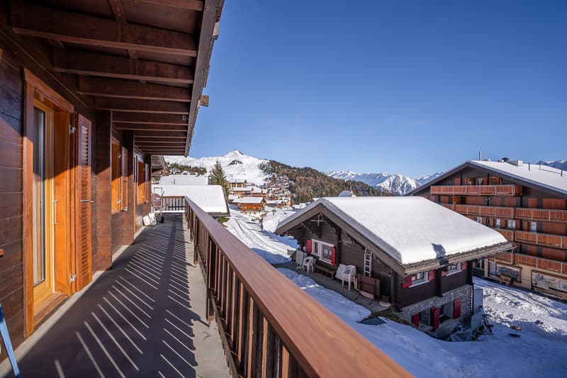 wooden exterior with balcony, snow on roofs