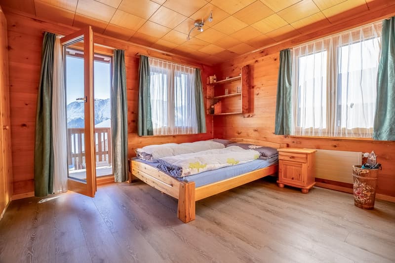 bedroom with bed, nightstand, balcony, wooden wall, wooden floor