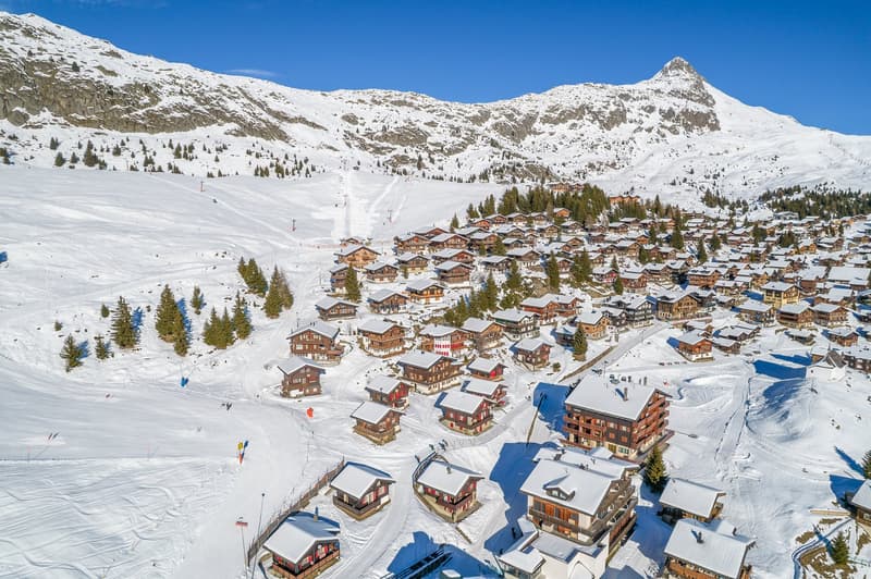 group of chalet style buildings with red trims and roofs covered in snow