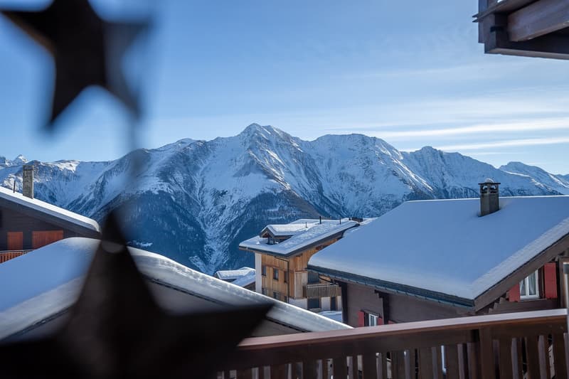 Building with wooden balcony overlooking snowy mountains