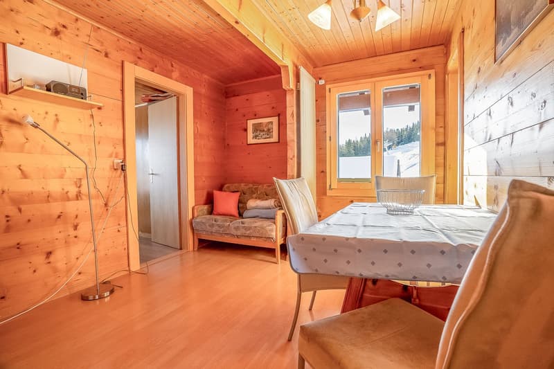 Wooden interior, wooden floor, a wooden sofa, dining table with four chairs, a lamp on the floor