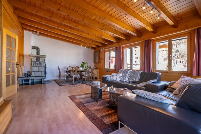 exposed wooden beams, fireplace, dining area with a wooden table and chairs, wooden floors, large windows